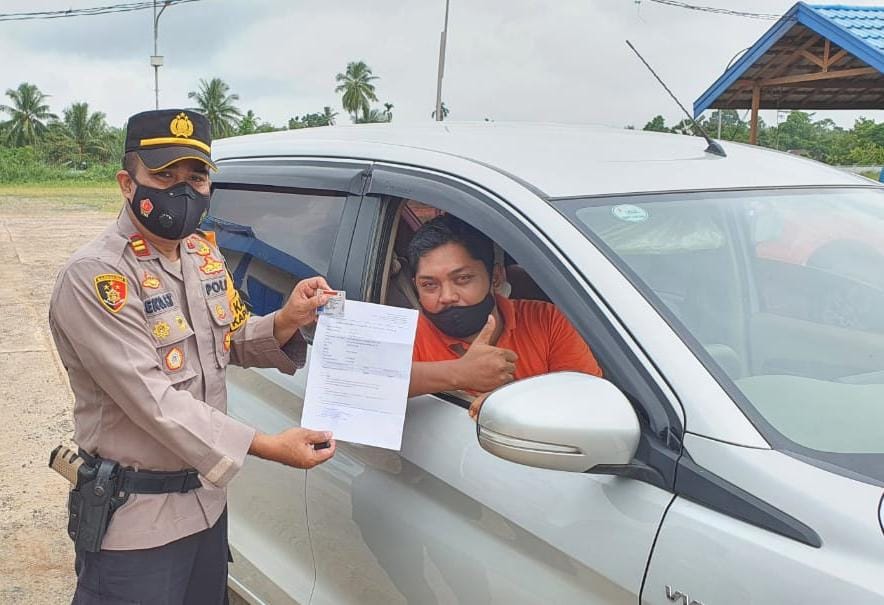 FOTO DOKUMEN BUKTI : Kapolsek Kapuas Timur Iptu Eko Sutrisno menunjukkan hasil rapid tes antigen salah satu pengendara yang akan melintas.
