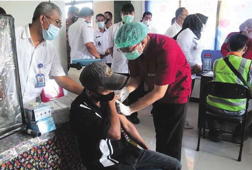 MELAYANI: Seorang dok-ter yang ber-tugas di salah satu puskemas melakukan proses penyu-tikan vaksin Covid-19 ke-pada warga