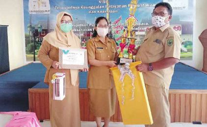 PENYERAHAN: Kadisarpustaka Kapuas Komari SE menyerahkan Piala dan Piagam Penghargaan kepada Kepala Desa Bungai Jaya Kadiman di Aula Disarpustaka Kapuas, belum lama ini.