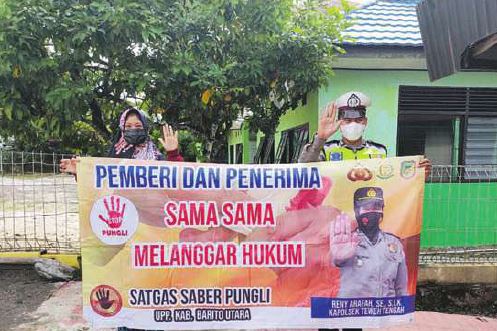 SOSIALISASI: Personel Bhabinkamtibmas Polsek Teweh Tengah jajaran Polres Barito Utara gencar sosialisasikan ajakan menolak pungutan liar (pungli) kepada warga di Jalan Yetro Singseng, kemarin