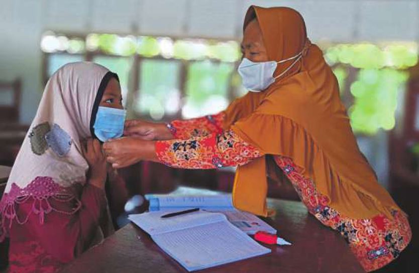 TERAPKAN PROKES: Guru di SDN-1 Talio Muara memasangkan masker bagi murid yang mengikuti bimbingan belajar mata pelajaran matematika, Sabtu (18/9) lalu