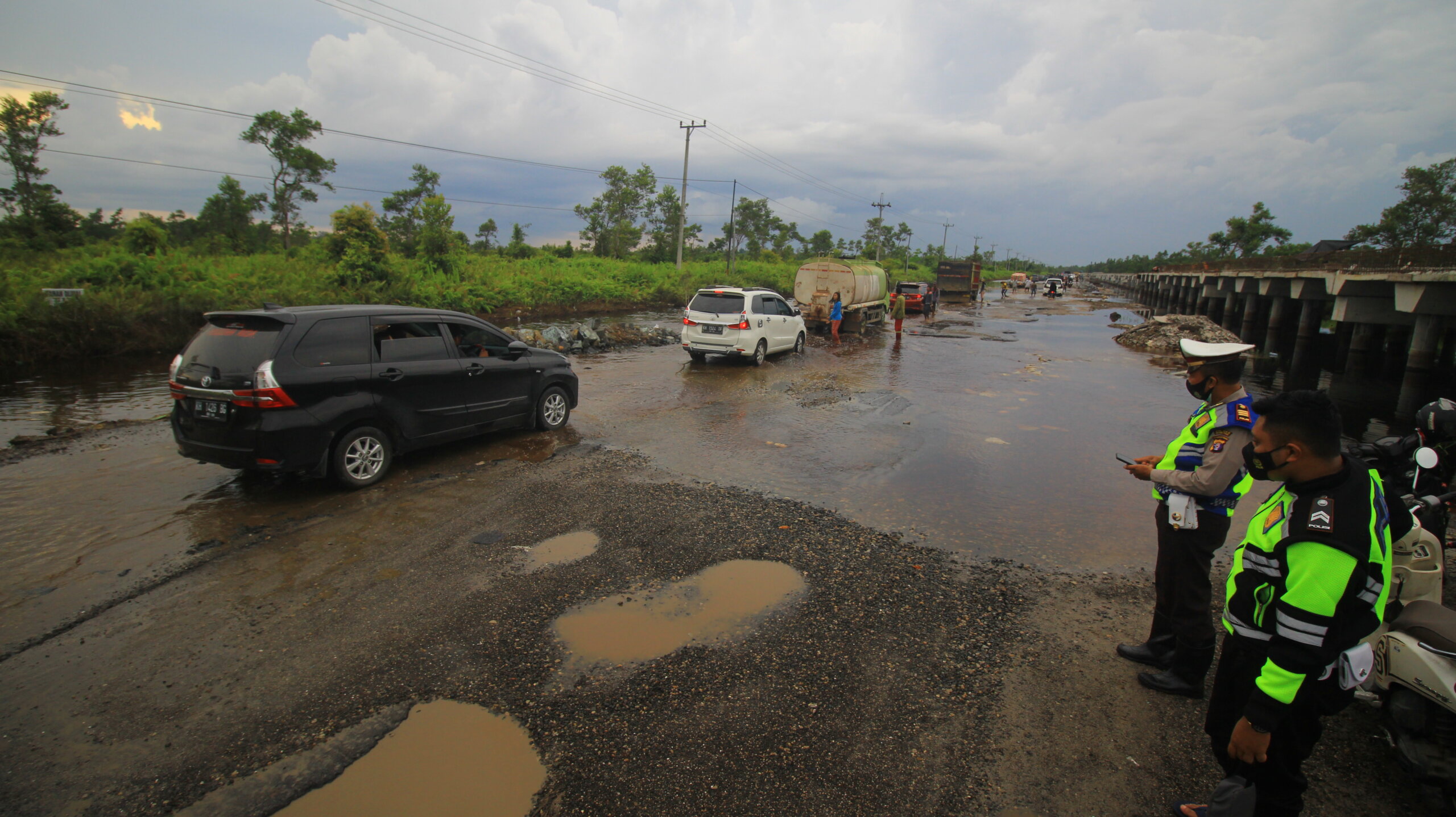 RUSAK PARAH: Personel kepolisian dari Satlantas Polres Pulang Pisau memantau arus lalu lintas di Jalan Trans Kalimantan Palangka Raya-Bukit Rawi, Minggu (10/10/2021)./DENAR
