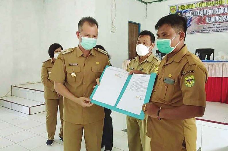 SERAHKAN BANTUAN : Bupati Gunung Mas Jaya Samaya Monong (kiri) menyerahkan bantuan bibit ikan dan bantuan sosial bagi korban banjir di Desa Hurung Bunut, belum lama ini.