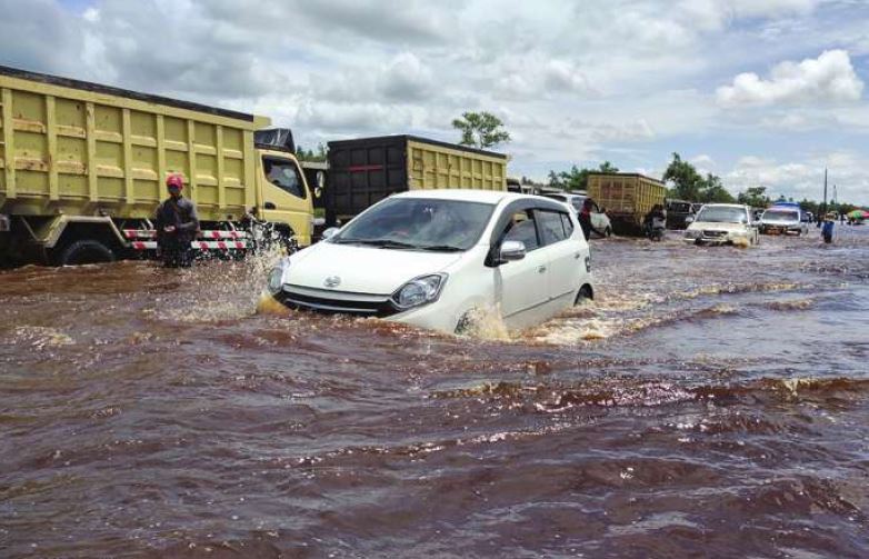 SEMAKIN MENINGGI: Pengendara kendaraan bermotor yang melintasi Jalan Penda Barania harus berhatihati. Mengingat ketinggian banjir di wilayah tersebut telah mencapai 60 centimeter.