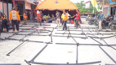 Petugas sedang mendirikan posko pengungsian bagi warga terdampak banjir