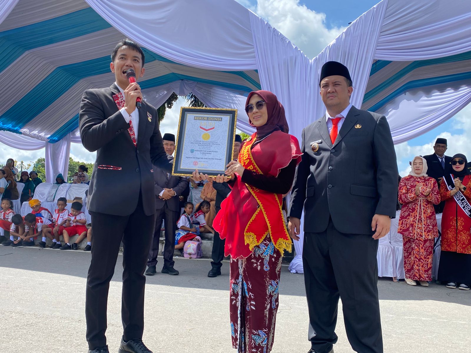 Bupati Lamandau, Rizky Aditya Putra. Mendampingi Ketua Bunda PAUD Kabupaten Lamandau, Norol Latifah. Menerima penghargaan Rekor MURI, di Bundaran Rusa Kota Nanga Bulik